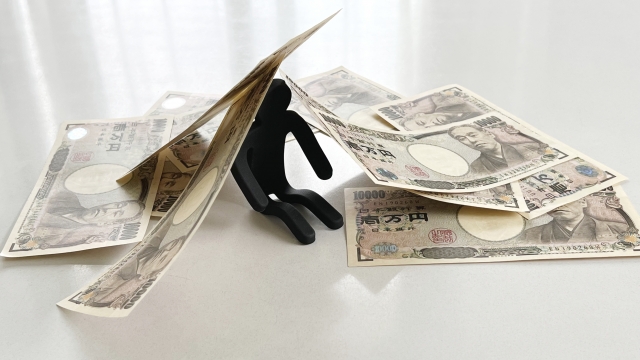 お金の上でうなだれる。丸亀市で借金返済の相談は無料でできます
